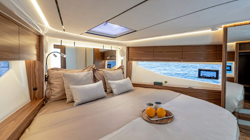 Master Cabin har mycket ljusinsläpp och en stor dubbelsäng. På bilden är det bäddat med överkast och kuddar i beige och sand. På ett träfat står två kaffekoppar och en bricka med två apelsiner på.