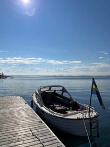 Liten öppen snipa vid en brygga. Sommar och nästan vindstilla.