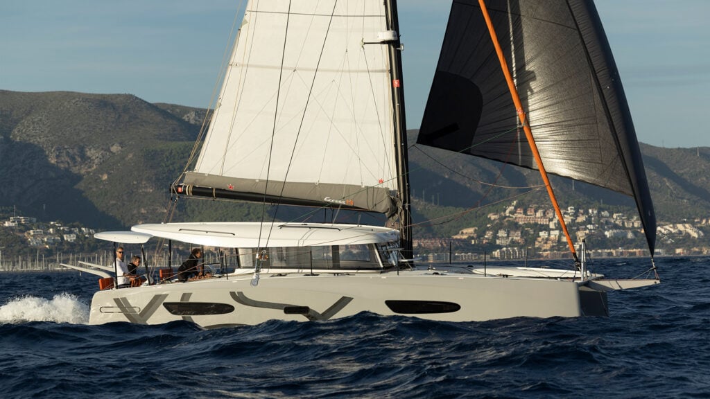 En segelbåt med grått skrov med svarta dekorationer på.