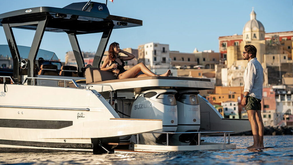 En man står på badplattformen som knappt syns i vattnet. På soldäck ligger en kvinna.